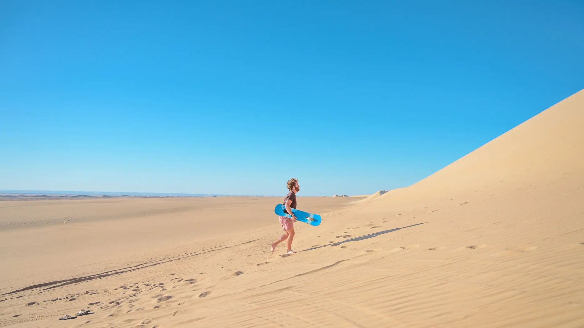 fes desert tour traveler skateboarding in the desert of Merzouga; sandboarding in the sahara desert; 