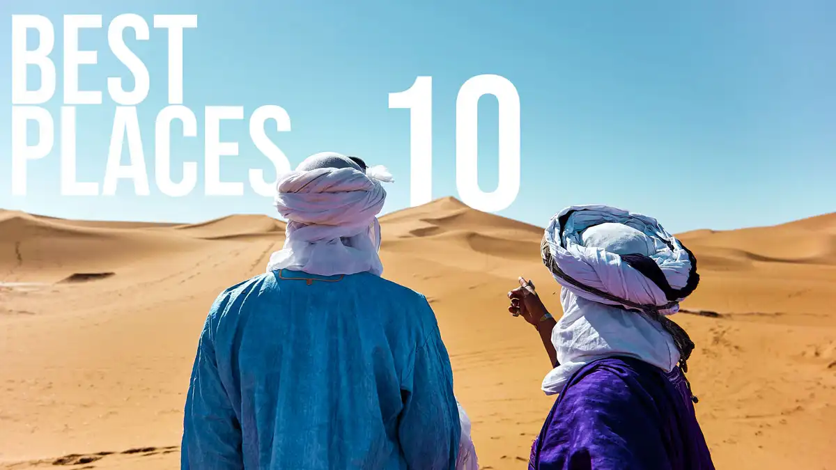 10 Best Places To Visit In Morocco - Travel Guide two men in the sahara desert pointing to the best 10 places to visit in morocco as a text on the sand dune